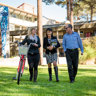 Three staff members walking on grass through campus