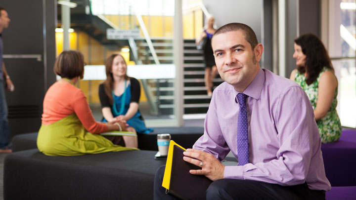 Professional male staff member looking at camera holding a notepad