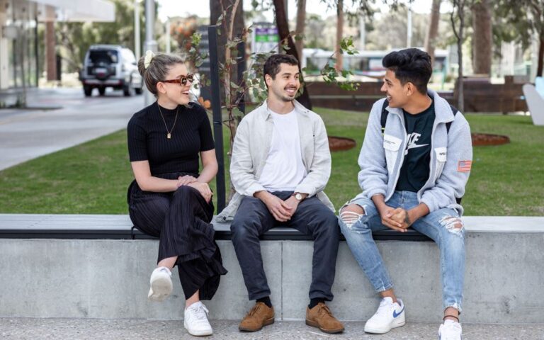 group of 3 people talking outside sat down